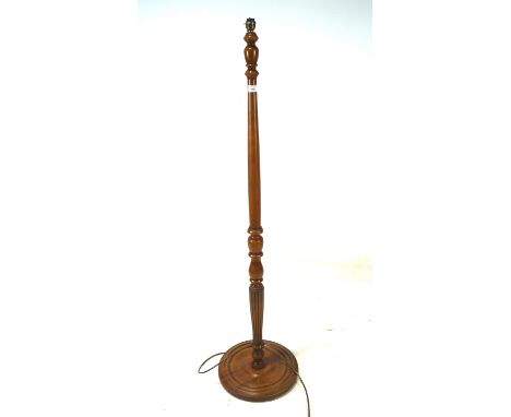 A turned wooden floor lamp, on a circular base, height (excluding fixtures) 140cm
