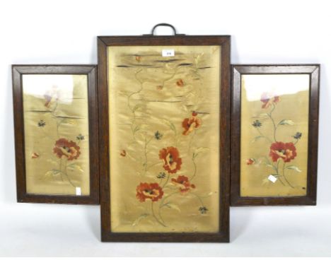 An early 20th century three fold folding fire screen, each containing a silk scene with floral motifs, mounted in oak frame, 