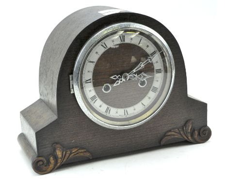 A British early/mid-20th century oak mantle clock of domed top, on scroll supports with carved foliate detail, Roman numerals