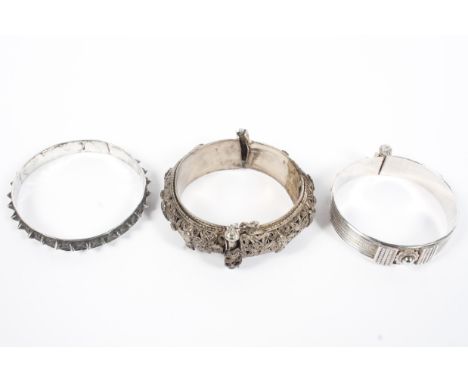 Three Omani style white metal bangle bracelets, some with filigree details, combined weight 133g