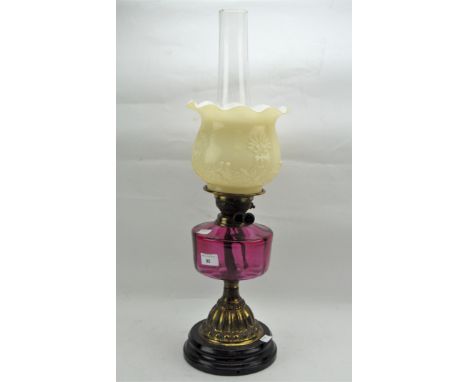 A 20th century duplex brass and glass oil lamp, with a fluted glass shade, a cranberry moulded glass reservoir and a clear gl