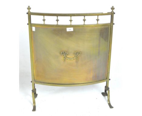 A 20th century fire screen, of curved form, the central copper panel featuring a motif, contained within a brass frame with f