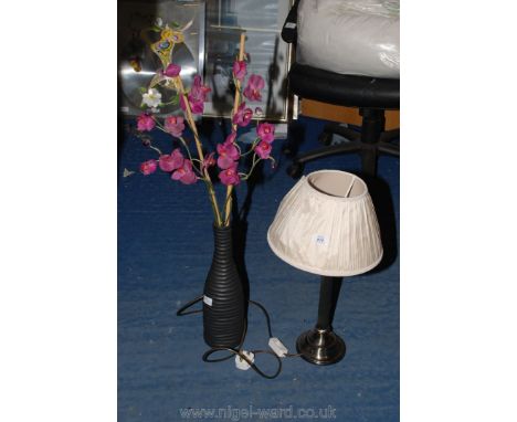 A table lamp and vase with artificial flowers.