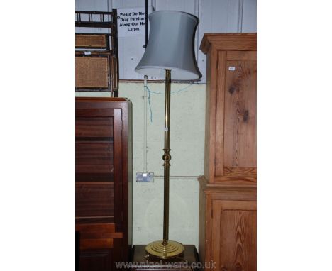 A brass standard lamp with shade.