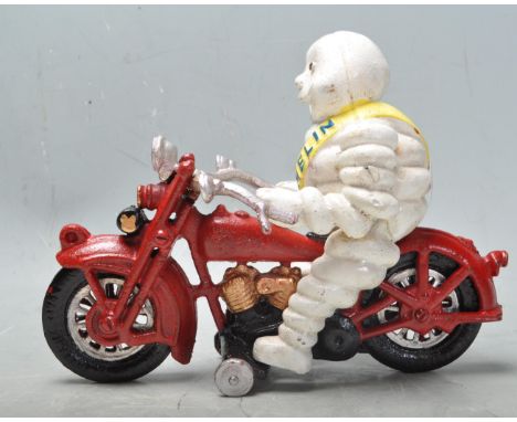 A vintage style cast metal polychrome Michelin man / Bibendum riding on a motorbike having the iconic yellow sash with Michel