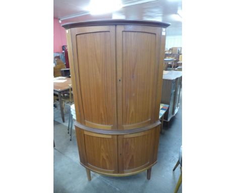 A teak bow front freestanding corner cabinet 