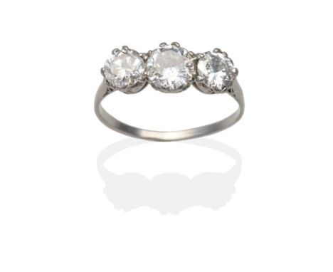 A Diamond Three Stone Ring, graduated round brilliant cut diamonds in white claw settings above a carved scroll gallery, to k