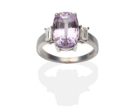 An 18 Carat White Gold Kunzite and Diamond Ring, an oval cut kunzite between baguette cut diamonds in claw settings, on a pla