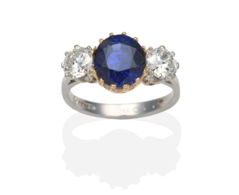 A Platinum Sapphire and Diamond Three Stone Ring, a round cut sapphire in a yellow claw setting between old cut diamonds in w