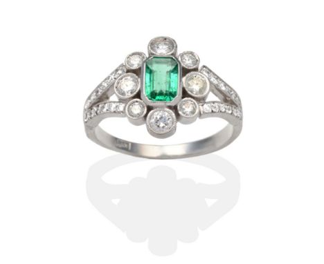 An Emerald and Diamond Cluster Ring, an octagonal cut emerald within a border of round brilliant cut diamonds in individual w