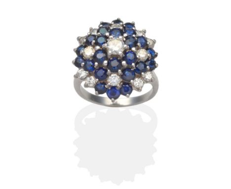 A Sapphire and Diamond Cluster Ring, a central round brilliant cut diamond within a graduated three tier border of round cut 