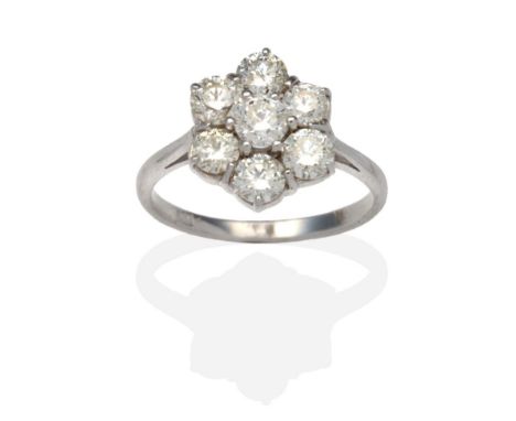 A Diamond Cluster Ring, seven round brilliant cut diamonds in white claw settings, to knife edge shoulders on a plain polishe