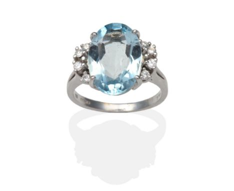A 14 Carat White Gold Aquamarine and Diamond Ring, an oval cut aquamarine in a claw setting and flanked each side by four rou