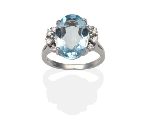 A 14 Carat White Gold Aquamarine and Diamond Ring, an oval cut aquamarine in a claw setting and flanked each side by four rou