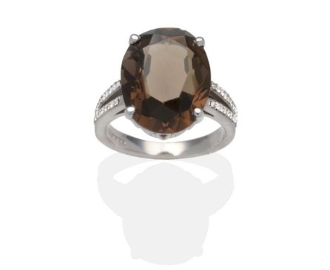 An 18 Carat White Gold Smokey Quartz and Diamond Ring, an oval cut smokey quartz in a claw setting above a pierced gallery, t