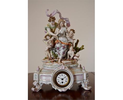 A late 19th/ early 20th century French porcelain clock, standing on four scrolling feet with circular white enamel dial, risi