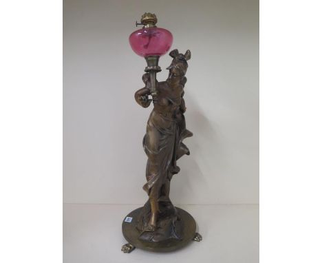 A bronze effect lady figure with a cranberry oil lamp on a bronze base, signed to base of figure, 72cm tall, generally good c