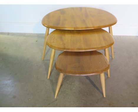 An Ercol blonde elm nest of 3 pebble tables, repair to base of largest otherwise good condition 