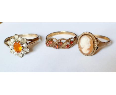 A 9ct gold dress ring with central orange cabochon surrounded by square cut and circular white stones in a floral design, tot