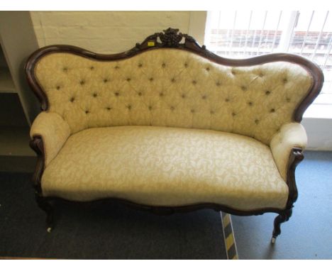 A Victorian carved mahogany, button back upholstered settee, two tone cream fabric with floral scrolled leaf pattern, serpent