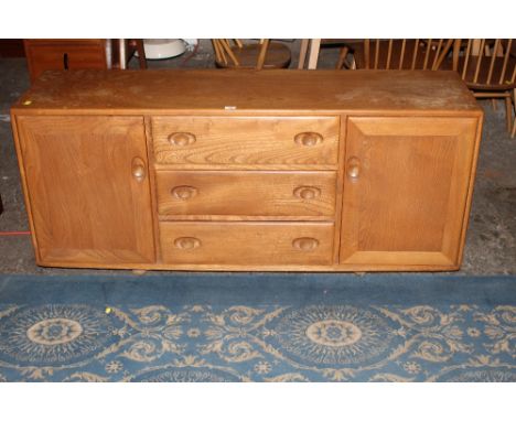 An ercol blond elm sideboard fitted 3 drawers flanked by cupboards 68 cm x 155 cm x 49 cm 