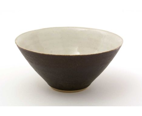 Dame Lucie Rie (1902-1995). A conical stoneware bowl with matte brown glazed exterior, cream interior and inner foot, moulded