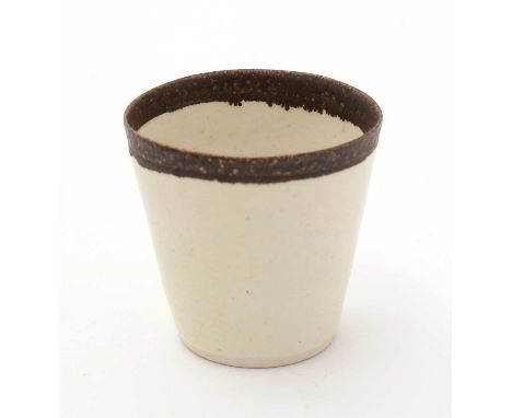 Dame Lucie Rie (19802-1995). A small porcelain bucket shaped cup with matte brown glazed rim and cream pitted body, moulded L