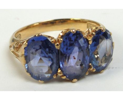 An 18ct gold three stone blue topaz ring set in scrolling mount, size K/L, approx 5.2g.
