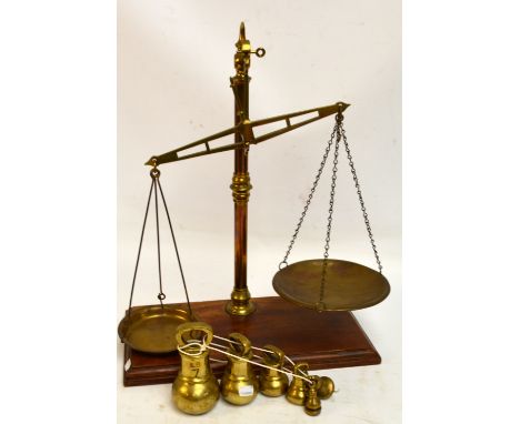 A set of balance beam scales by Perry & Warmington, with a set of six graduated bell shaped brass weights.