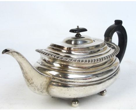A George V hallmarked silver teapot of oval form, raised on four bun supports with wooden handle and finial, Sheffield 1930, 