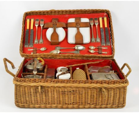 A vintage wicker four setting picnic hamper, comprising plates, cups and saucers (one cup missing), cutlery and flatware, a k