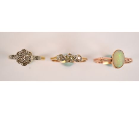 A 9ct rose gold and opal ring, an 18ct yellow gold and platinum mounted diamond cluster ring and a further gold and three sto