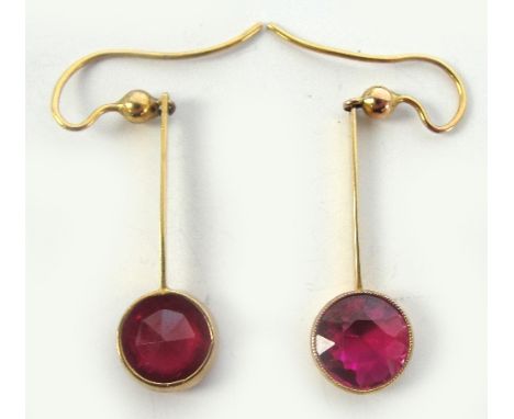 A pair of yellow metal ruby drop earrings both with circular cut stones suspended on a simple bar, length of drop 2.5cm, diam