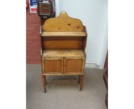 An early 20th century side cabinet with twin cupboard doors below a shelf with arched pediment, raised on square tapering leg