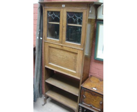 An Arts and Crafts bookshelf with chequered stringing decoration with overhanging cornice above brackets, the top glazed sect