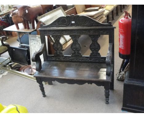 A late Victorian carved oak bench with three shaped panels to the back, with ring turned front legs, width 106cm, depth 40cm,
