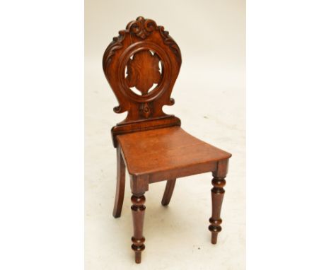 An early Victorian oak hall chair with carved scrolls to the back and with ring turned front legs, height 89cm (af).