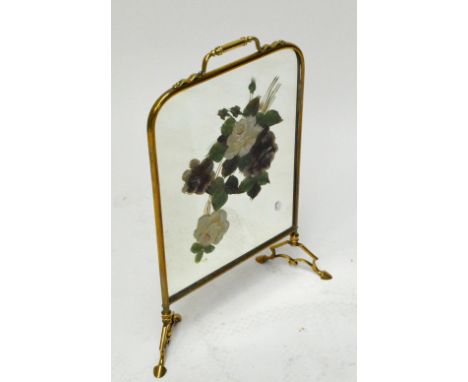 A brass framed mirrored firescreen, hand painted with floral sprays to one side, height 70cm.