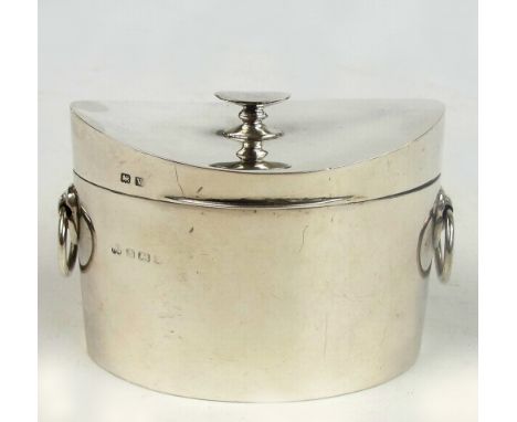 A George V hallmarked silver shaped oval tea caddy of plain form with twin ring handles and cast handle to the hinged lid, ma