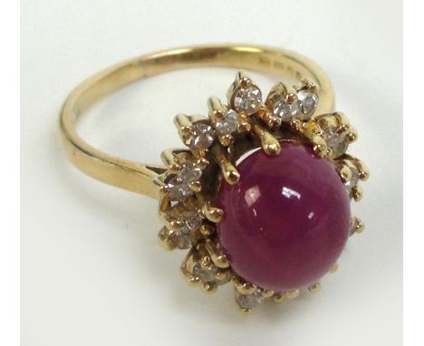 An 18ct gold diamond and star ruby ring, the central oval cabochon ruby within a border of stepped diamonds in high scroll mo