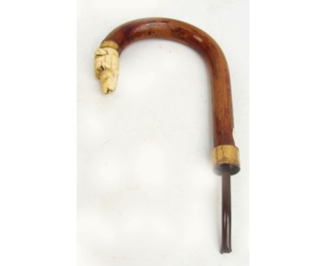 A late Victorian novelty carved ivory and wood walking stick/umbrella handle, the tip modelled as a dog's head (lacking eyes)