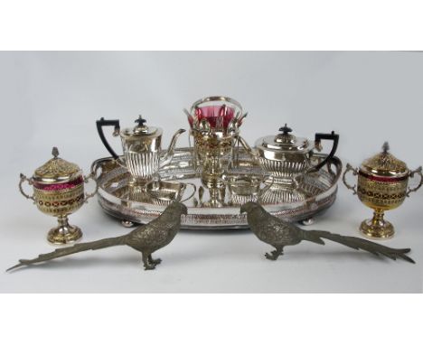 A group of electroplated items comprising a four piece tea set, a pair of twin handled goblets with covers and ruby glass lin