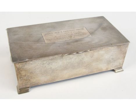 A George VI hallmarked silver rectangular cigarette box, centred with a rectangular cartouche with presentation inscription "