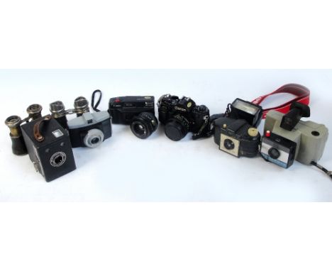 A collection of cameras and camera equipment including a Canon A-1, a cased box Brownie, Polaroid, etc, and two pairs of fiel