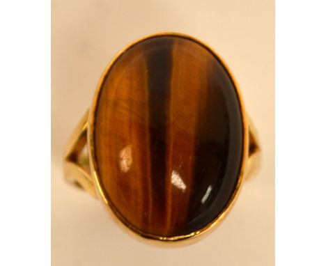 A 9ct gold dress ring set with a large oval tiger's eye cabochon, size U/V, approx 12.4g.