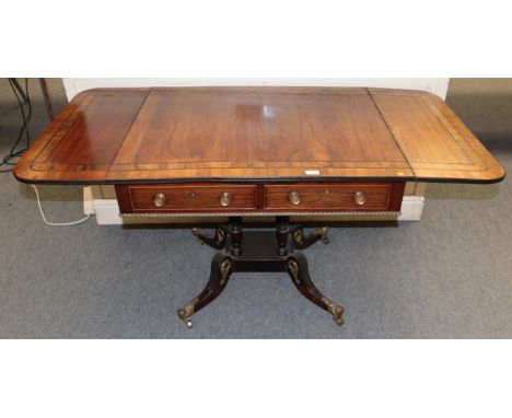 A Regency rosewood, ebony strung and gilt metal mounted sofa table, early 19th century, with two rounded drop leaves and reed