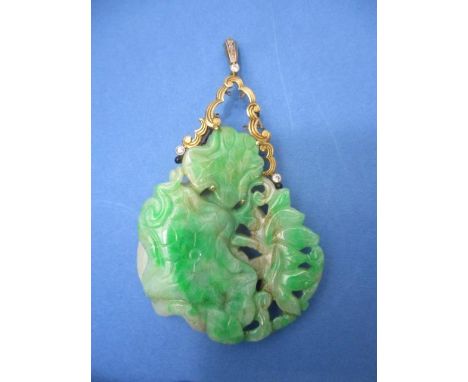 A green and grey carved jade pendant decorated with flowers and an insect set in a white, yellow and gold coloured metal fram