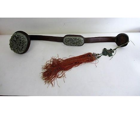 A 19th century and later green jade ruyi scepter with two carved oval panels, decorated with flowers and dragons, on a hardwo