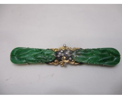 A white and yellow gold coloured metal brooch set with ten diamonds and cloud designs, flanked by a pair of carved jade oval 