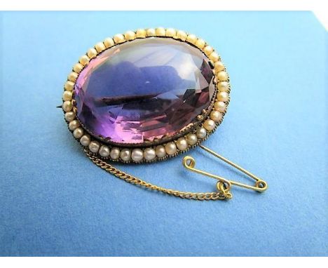 A Victorian yellow metal brooch set with an amethyst within a border of seed pearls, 31mm x 25mm, boxed 